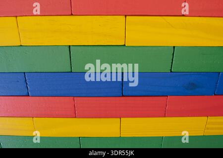 Close-up of a wall made from brightly colored wooden toy blocks arranged in a neat geometric pattern and texture, suitable for a background Stock Photo