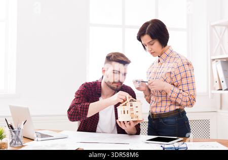 Couple Works Together on a Model House at a Workspace in the Afternoon Stock Photo