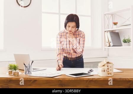 Designer Works on Architectural Plans in an Office During Daytime Hours Stock Photo