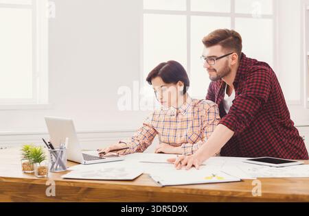 Two People Working on a Project Together in a Bright Office Space With Laptops and Papers Stock Photo