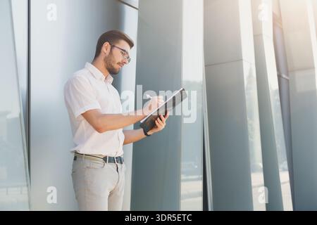 A Young Man Stands Outside a Building With a Modern Design Stock Photo