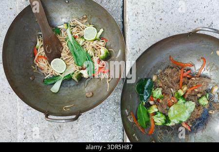 Collection of Cooking Dishes in Two Woks Showing Various Ingredients and Preparation Methods Stock Photo