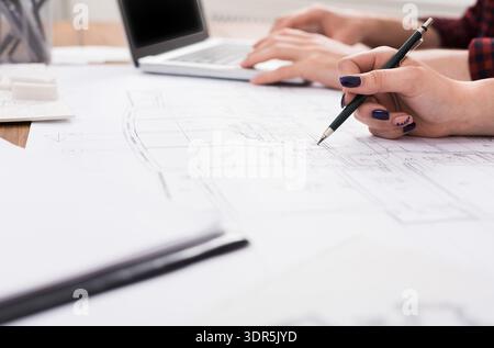 Group of People Working on Architectural Plans With a Laptop in a Workspace Stock Photo