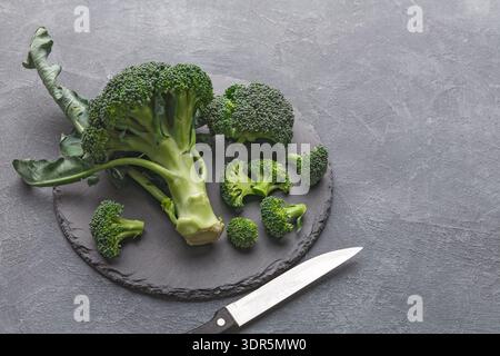 Fresh Broccoli on a Slate Board With a Knife Placed Beside It for Preparation Stock Photo