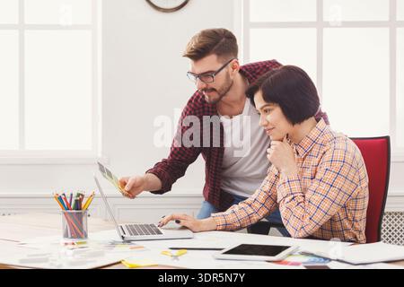 Two People Working Together in an Office on a Computer While Discussing a Project Stock Photo