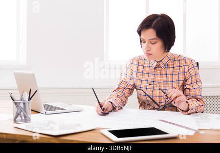 Woman Working on Design Plans in a Bright Office Space During the Daytime Stock Photo