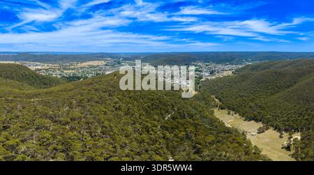 Drone aerial photograph of the town of Lithgow against a vibrant blue cloudy sky as viewed across a forest in a valley in the Central Tablelands of Ne Stock Photo