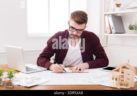 Designer Works on Project Plans in a Modern Office Setting During Daytime Hours Stock Photo