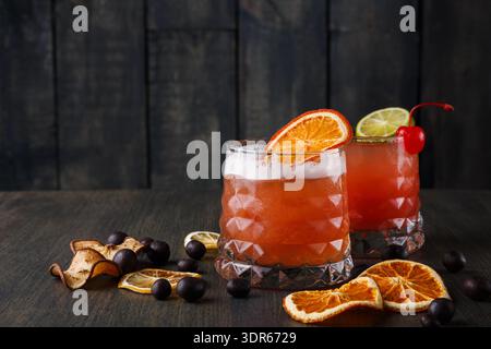 Two Cocktails With Fruit Slices and Dried Fruit on a Dark Wooden Table During an Evening Gathering Stock Photo