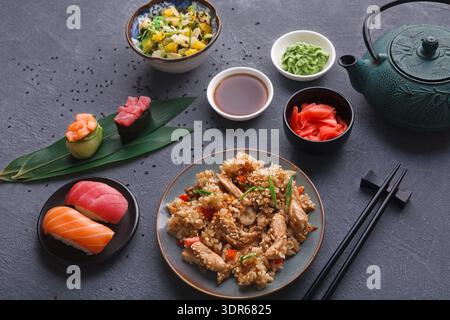 Collection of Sushi, Fried Rice, and Side Dishes on a Table With Tea Set Stock Photo