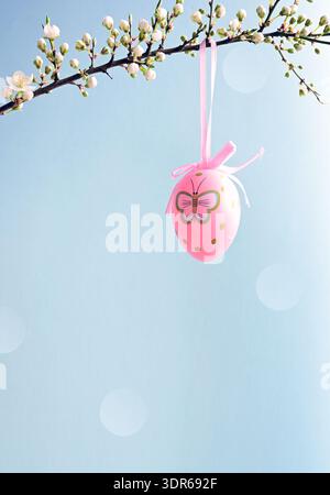 Branches of cherry blossoms are decorated with Easter eggs against blue sky. Holiday concept. Religious holiday Easter. Nature. Spring background. Stock Photo