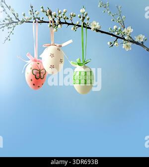 Branches of cherry blossoms are decorated with Easter eggs against blue sky. Holiday concept. Religious holiday Easter. Nature. Spring background. Stock Photo