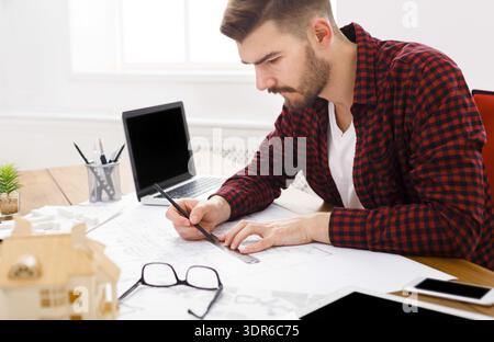 Man Working on Architectural Plans in a Modern Office Space During Daytime Stock Photo