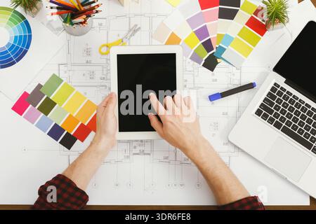 Designer Works on Tablet With Color Swatches and Laptop on Drafting Table During Day Stock Photo
