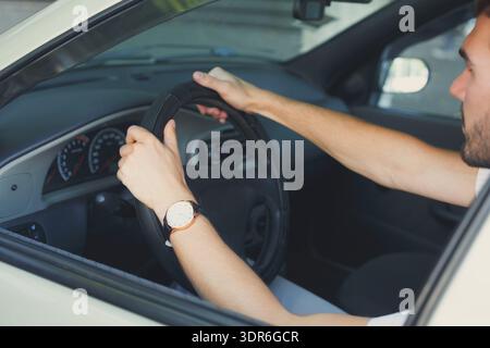 Hands on the Steering Wheel Inside a Car During a Drive on a Sunny Day in the City Stock Photo