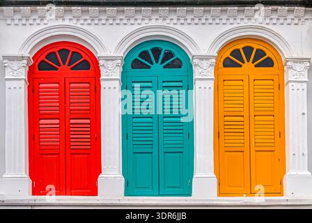 Three colorful red, green and yellow window shutters in Chinatown, Singapore. Stock Photo