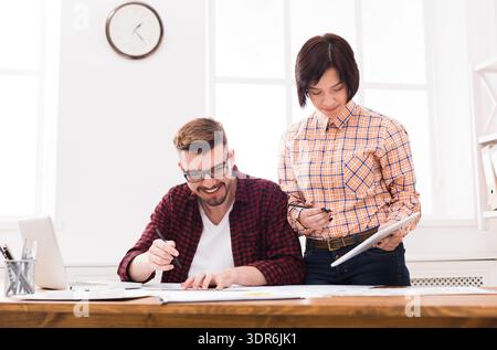 Two People Working Together on a Project in a Bright Office Space During the Day Stock Photo