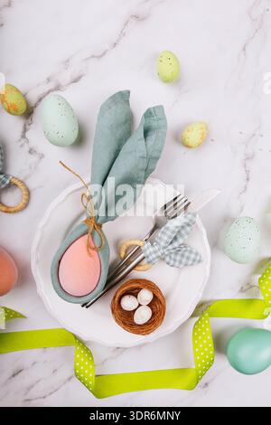 Easter Bunny Napkin and Cutlery on Plate with Pastel Eggs Stock Photo