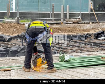 Denver, Colorado, USA - 2 June 2025: Construction worker using a power tool to cut lengths of steel wire for reinforced concrete Stock Photo
