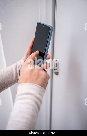 Hands holding a mobile phone, interacting with an app for home security and smart access control technology Stock Photo