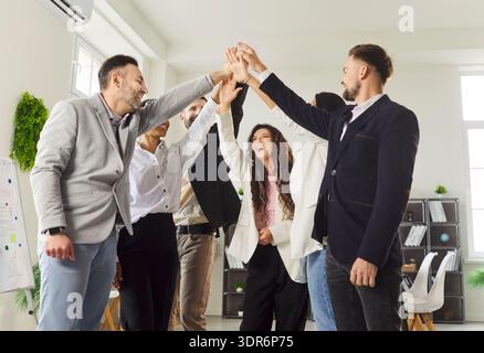 Happy businesspeople stacking their hands together as gesture of collaboration, unity and success Stock Photo