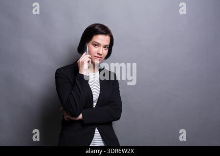 Businesswoman on Phone in Studio With Gray Background During a Work Session Stock Photo