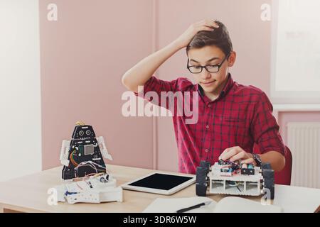 Boy Works on Robot Project With Tablet and Robotics Kit in Classroom During Afternoon Stock Photo