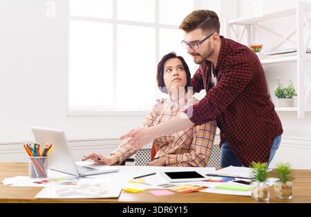 Team Members Discuss Project Details While Working at a Desk in a Bright Office Space During the Day Stock Photo