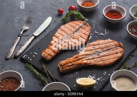 Freshly Grilled Salmon With Spices and Herbs on a Black Slate Serving Board in the Kitchen Stock Photo