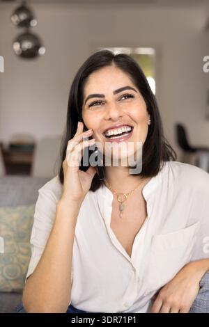 Cheerful positive young Latin phone user woman talking on cell Stock Photo