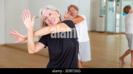 Active mature woman learning dynamic dances in choreography class Stock Photo