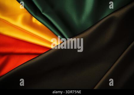 Black History Month background. Red, yellow, green colors drapery on black silk satin background Stock Photo