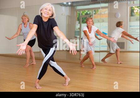 Smiling mature woman enjoying active dancing in dance studio Stock Photo