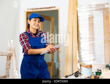 Cheerful woman engineer checking documents in new apartment Stock Photo