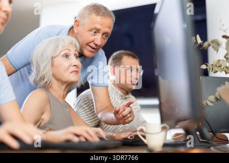 Older mentor explaining something to elderly woman during computer class Stock Photo