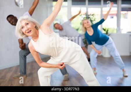 Active mature men and women practicing Jazz-funk dance in training hall Stock Photo