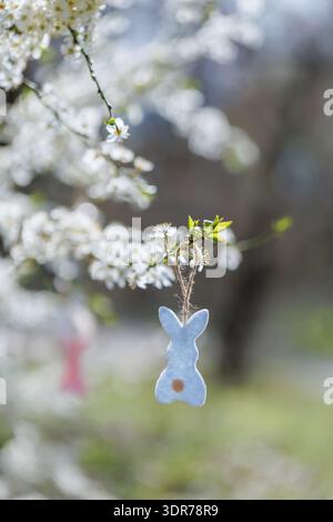 Blue felt bunny hanging from blooming tree branch in spring Stock Photo