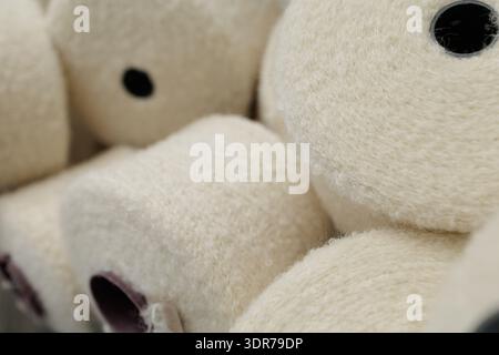 Closeup of boucle yarn cones with looped texture prepared for weaving, illustrating specialty textile material for fabric production and apparel marke Stock Photo