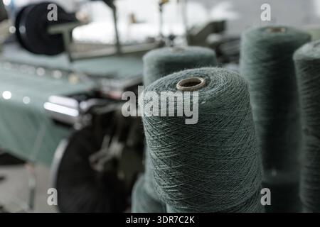 Closeup of yarn spools mounted on weaving machine in textile factory, ideal for manufacturing, supply chain, and industrial production marketing. Stock Photo