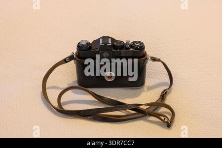 Vintage Zenit SLR film camera in a black leather case on a neutral background Stock Photo