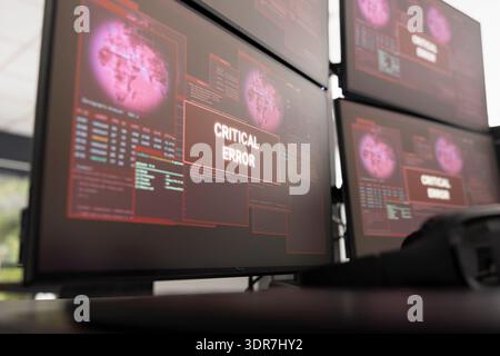 Computer workstation displays operating system error message, indicating critical system or file failure. Vacant office with desktop monitors showing malfunction alerts, symbolizing IT disruption. Stock Photo