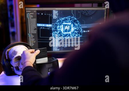 Hacker using hard drive with sensitive information obtained by running neural network software to breach company locked databases. Man uploading stolen data on SSD after finishing cyber attacks Stock Photo