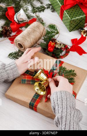 Hands Wrap a Gift With a Bell and Ribbon During a Holiday Preparation Session Stock Photo