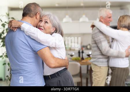 Two married couples enjoying slow dancing at house party for friends Stock Photo