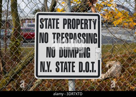 Horizontal photo of a white "State Property No Trespassing No Dumping" sign on a fence in New York, USA - state property warning, no trespassing Stock Photo