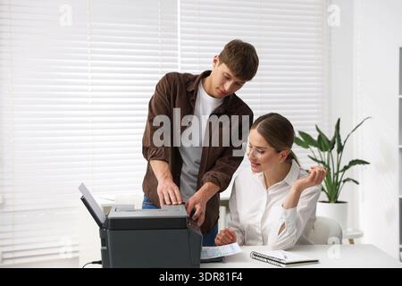 Office workers using printer at white desk indoors Stock Photo