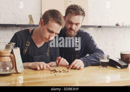 Two Men Focus on Coffee Beans While Working in a Coffee Shop During the Daytime Stock Photo