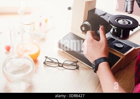 Student Conducts Experiment Using Microscope and Laboratory Equipment in a Science Classroom Stock Photo