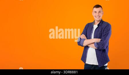 Cheerful Young Man Standing Crossing Hands Posing Over Blue Background Stock Photo