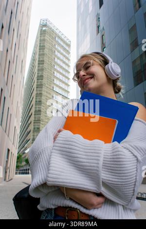 Smiling woman student walking on urban campus holding books Stock Photo